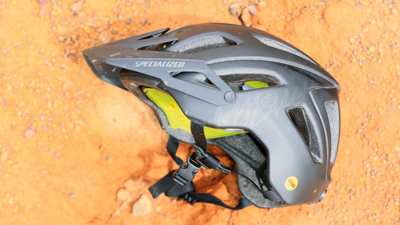 The Specialized Ambush MTB helmet on its side on a dirt road