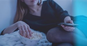 Snap test: We tasted five microwave popcorns; this one came out tops A woman having popcorn and watching TV.