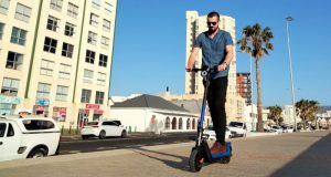 NIU KQi3 Sport Electric Kick Scooter – Review A young man riding an electric kick scooter on Strand promenade, South Africa
