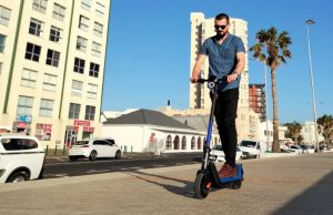 NIU KQi3 Sport Electric Kick Scooter – Review A young man riding an electric kick scooter on Strand promenade, South Africa