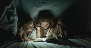 Eurolux Rechargeable 3W LED Emergency Light – Review A women holding a torch, reading to a boy and girl while under a sheet.