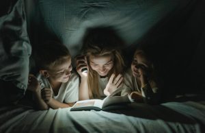 Eurolux Rechargeable 3W LED Emergency Light – Review A women holding a torch, reading to a boy and girl while under a sheet.